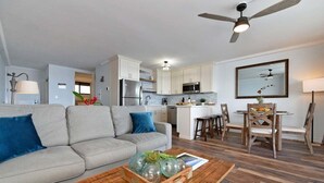 Ein modernes Wohnzimmer mit grauem Sofa, Holztisch und einem Essbereich mit Holztisch und Stühlen.
