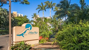 Schild für Maui Kai Kaanapali Beach, umgeben von üppiger Vegetation und Palmen.