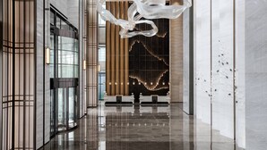 A modern lobby with a reflective floor, a large abstract sculpture, and a reception desk. - Zhangjiagang Marriott Hotel (Suzhou)