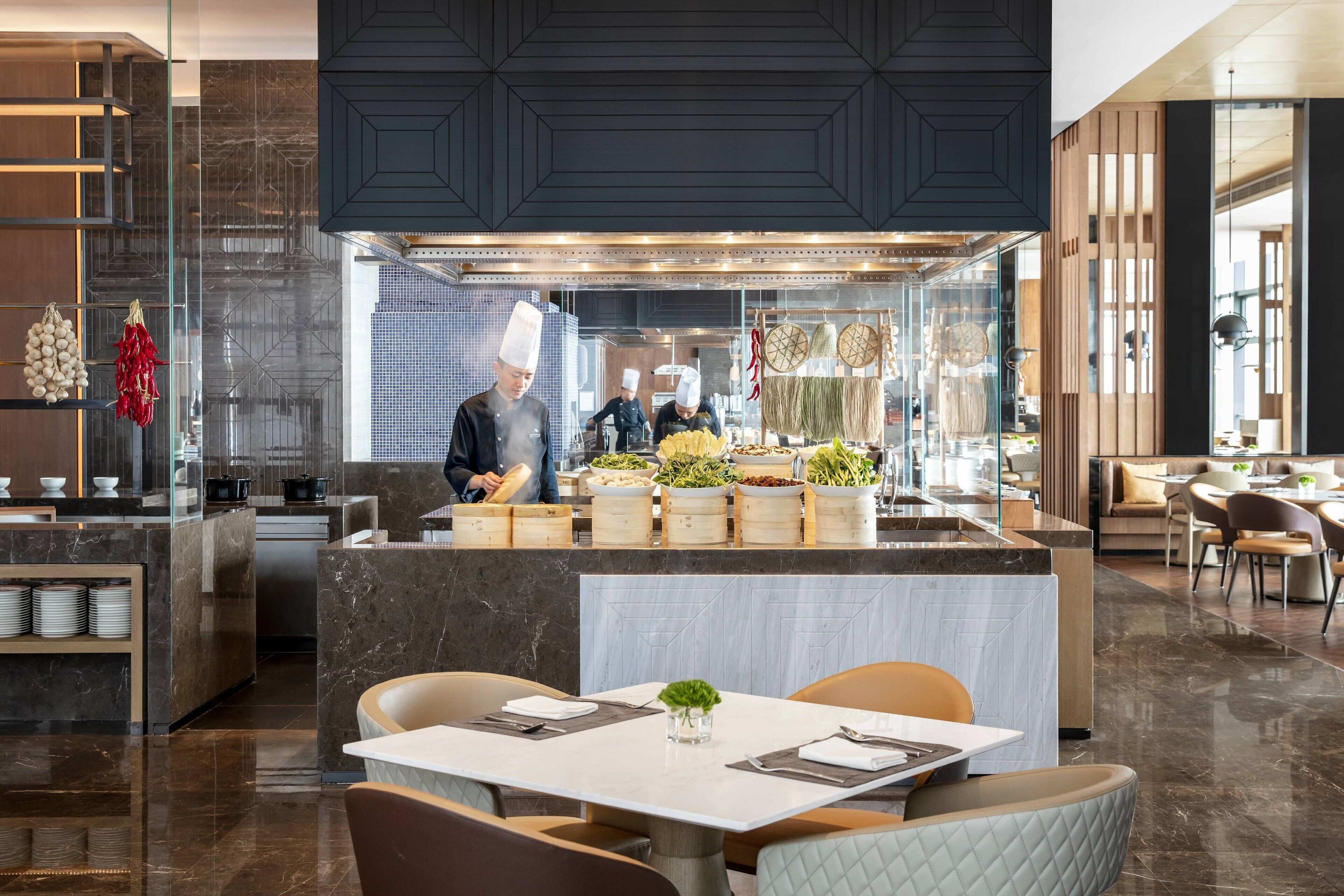 Een modern restaurant met een centraal eiland, een zithoek en een keuken op de achtergrond.