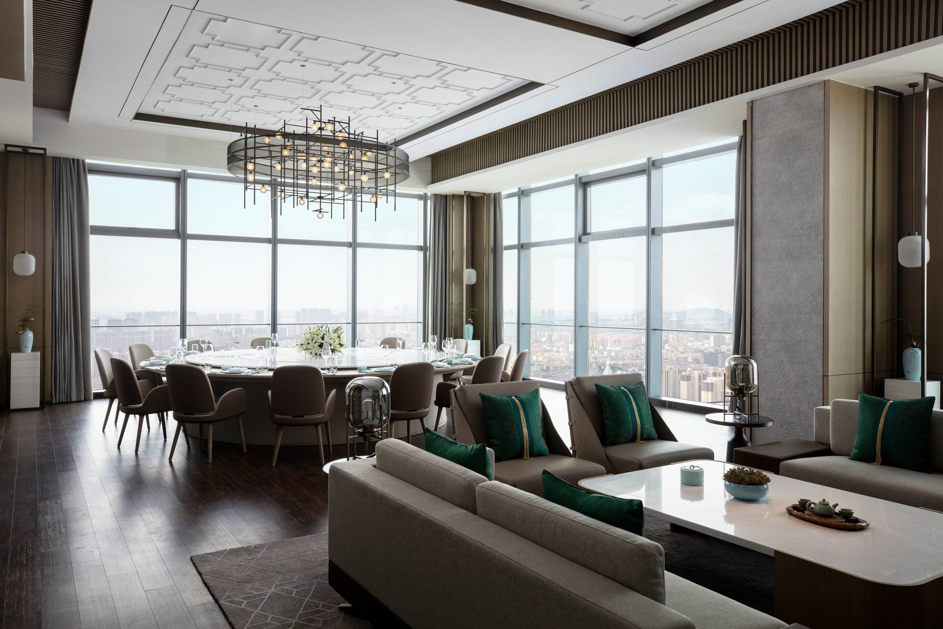 Ein modernes Interieur mit Essbereich, Sofas und großen Fenstern mit Blick auf die Stadt.