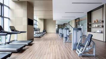 Un gimnasio moderno con cintas de correr, elípticas y pesas libres.