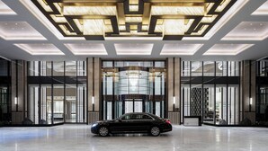 A modern hotel lobby with a black car parked in front, large glass doors, and a geometric ceiling design. - Zhangjiagang Marriott Hotel (Suzhou)