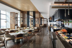 Um restaurante moderno com pé-direito alto, divisórias de madeira e um balcão comprido com diversos alimentos.