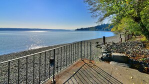 Eine Uferpromenade mit Metallgeländer, Kieselsteinen und freiem Blick auf das Wasser.