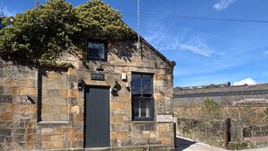 Un edificio de piedra con un letrero que dice "Abbey House" y otro indicando "Acceso para Vehículos Grandes".