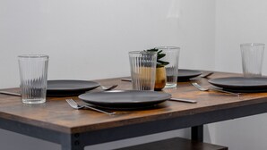 Una mesa de comedor con platos negros, cubiertos y vasos transparentes.