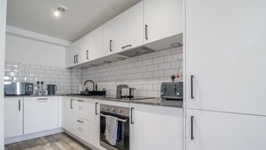 Cocina moderna con armarios blancos, horno de acero inoxidable, tostador empotrado y salpicadero de azulejos.