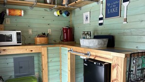 Une cuisine compacte dotée de meubles en bois, d’un four à micro-ondes, d’une machine à café et d’un lave-vaisselle.