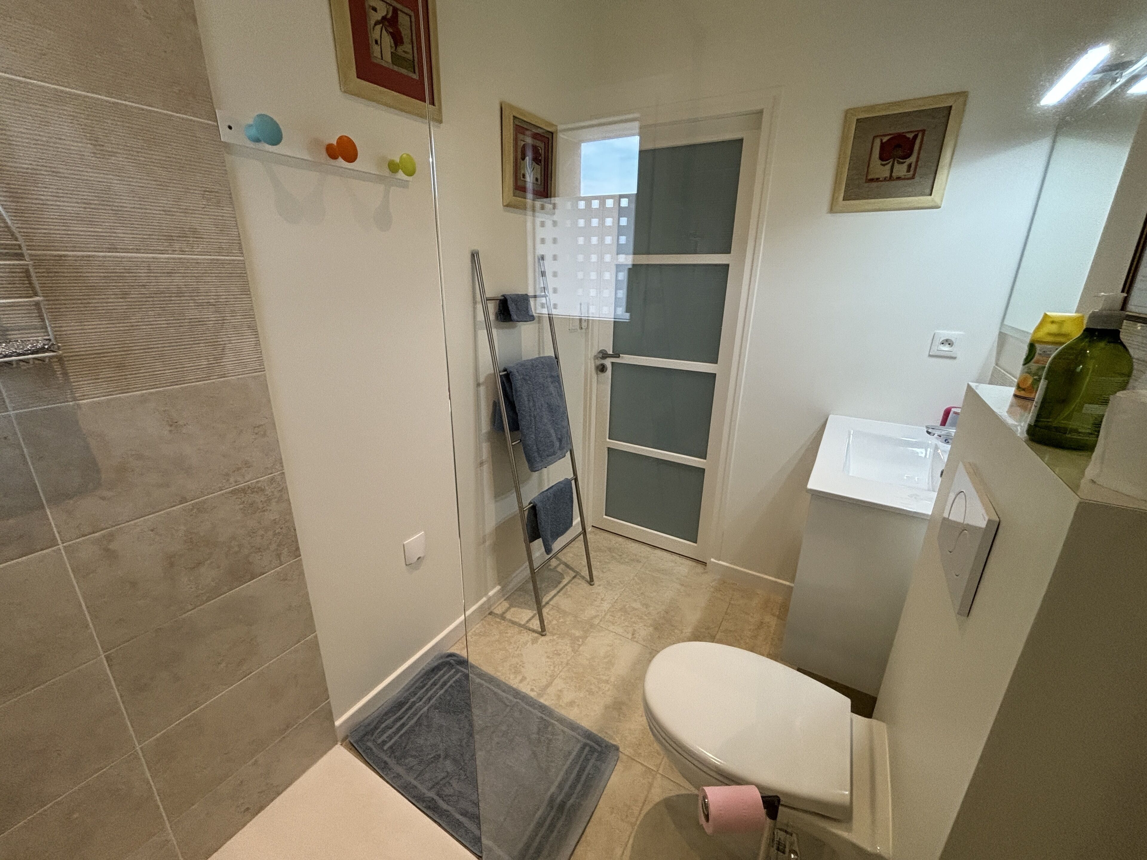 A small bathroom with a toilet, a shower, and a towel rack.