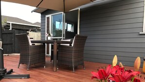 An outdoor patio with a table and chairs, a grill, and potted plants.