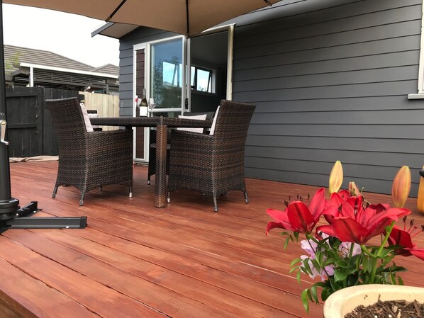 Un patio al aire libre con mesa y sillas, una parrilla y plantas en macetas.