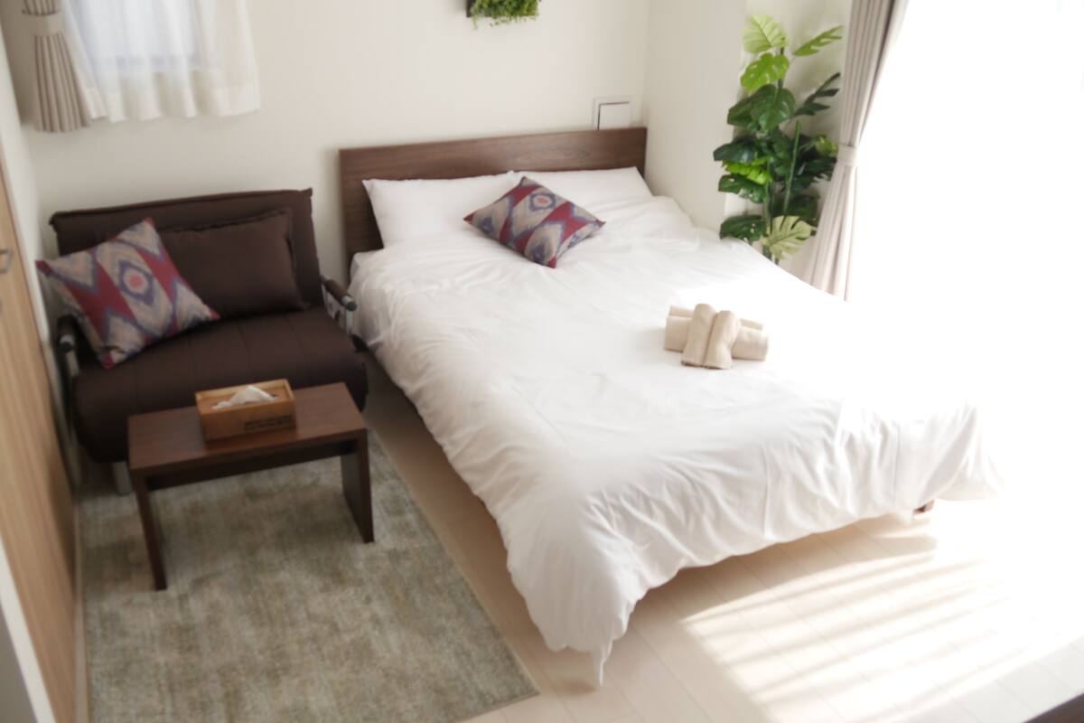 Ett hotellrum med en säng, en soffa, ett litet bord och en växt.