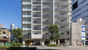 Um edifício de vários andares com design arquitetônico moderno, com uma série de varandas e uma placa grande no topo.