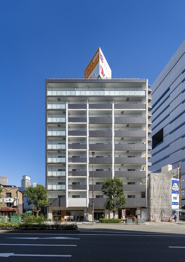 A multi-story building with a modern architectural design, featuring a series of balconies and a prominent sign at the top.