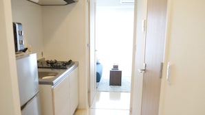 Um corredor estreito que leva a um quarto com uma cama e uma mesinha.