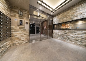 A modern lobby with stone walls, a glass elevator, and a 'Meet' sign.