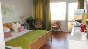 Quarto de hotel com uma cama, uma escrivaninha, televisão e uma janela com cortinas.