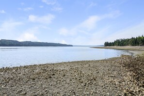 A rocky shoreline with calm water and distant hills. - Charming little red beach house (Hoodsport)