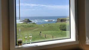 Een uitzicht op de oceaan, een begroeiend landschap en een fles Aminta wijn.