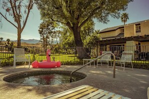 Zona de piscina con un flotador de flamenco, sillas y vistas a un campo de golf y montañas.