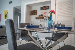 Un comedor con una mesa de vidrio, sillas grises y platos azules.