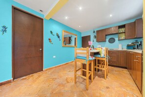 A kitchen with wooden cabinets, a dining table with chairs, and a blue wall.