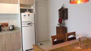 A compact kitchen with a white refrigerator, wooden cabinets, and a dining table with chairs.