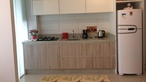 A kitchen with wooden cabinets, a gas stove, a sink, and a refrigerator.