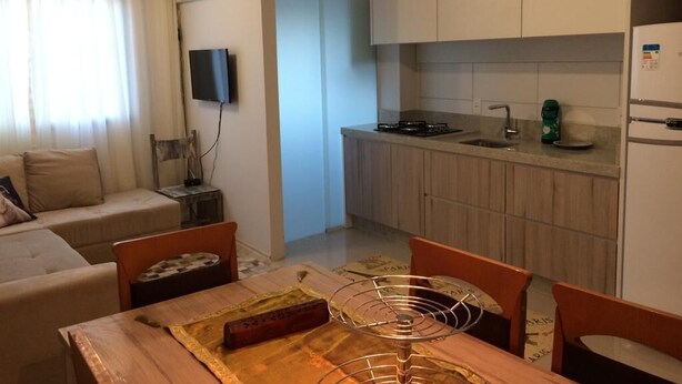 A compact living space with a kitchenette, a dining area with a table and chairs, and a sofa.