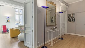 Una habitación con un espejo grande, una mesita consola blanca y una silla roja.