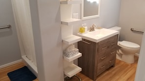 A bathroom with a white sink, a wooden vanity, a toilet, and a mirror above the sink.