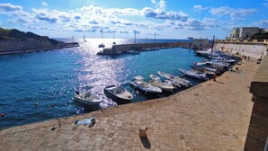 Un port où des bateaux sont amarrés le long des quais, un ciel dégagé et une vue lointaine d’un bâtiment.