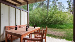 A wooden table with four bottles of Coca-Cola, set against a backdrop of trees and a covered patio area. - RMR: Chokeberry 3813 Condo in The Aspens (Wilson)