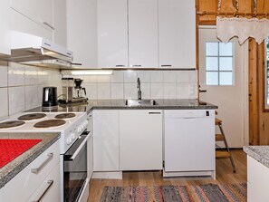 A modern kitchen with white cabinetry, a Bosch dishwasher, a coffee maker, and a red mat on the stove. - Kultaranta by Interhome (Juuka)