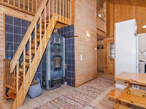 A wooden interior with a fireplace, a staircase, and a dining area. - Kultaranta by Interhome (Juuka)