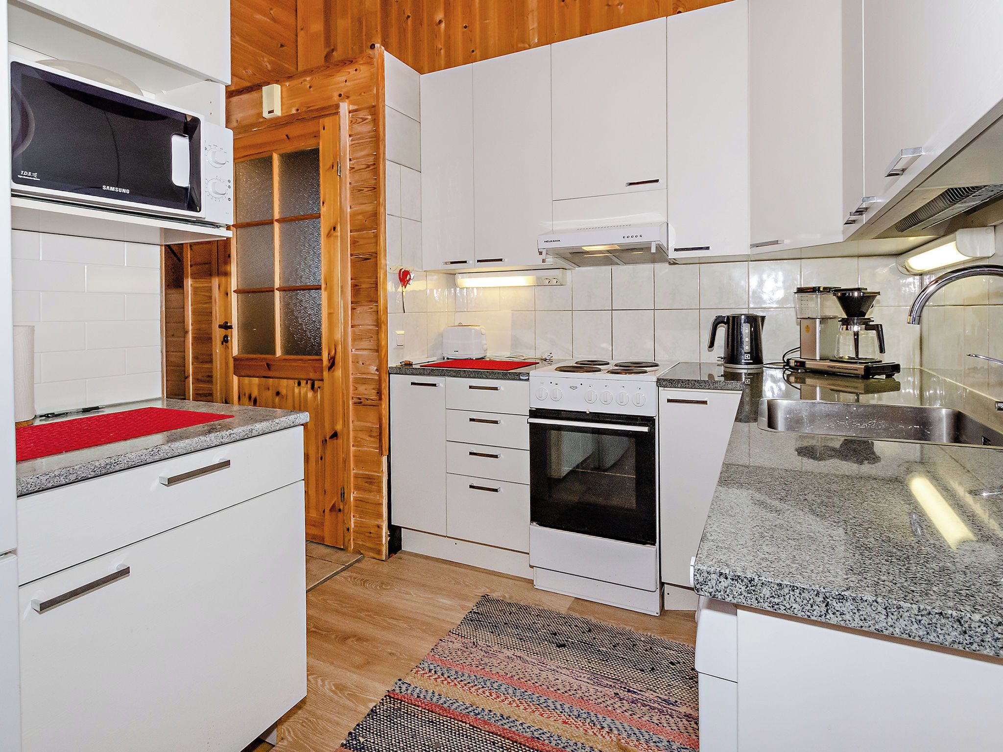 Una cocina moderna con armarios blancos, un microondas, una estufa y una cafetera.