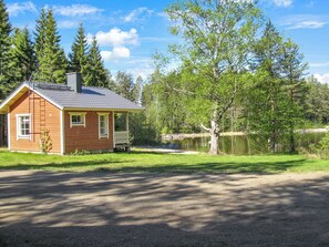 A cabin with a porch, a small pond, and a forested area. - Kultaranta by Interhome (Juuka)