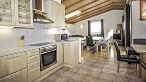 A modern kitchen with wooden cabinets, a microwave, and a built-in oven. - Vacation home Dialer by Interhome (Umhausen)