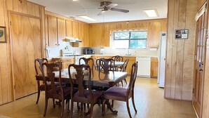 A wooden-paneled kitchen with a dining table and chairs, a ceiling fan, and a window. - Ranch Style House 1/2 Block from Fulton Park & Fishing Pier on Aransas Bay. (Fulton)