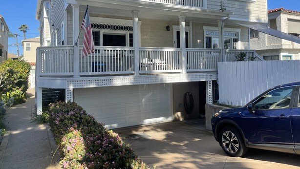 A two-story house with a balcony, a garage, and a driveway.