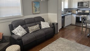 A modern kitchen with white cabinets, a stainless steel stove, and a microwave.