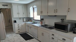 A kitchen with white cabinets, a sink, a stove, and a microwave.