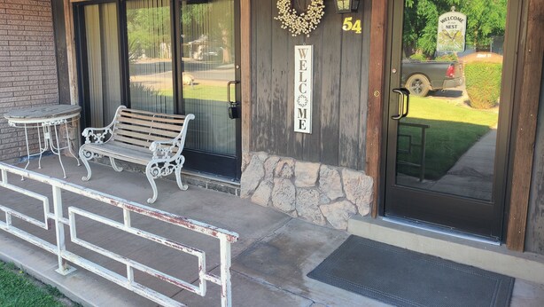 A wooden building with a welcome sign, number 54, and a bench outside.