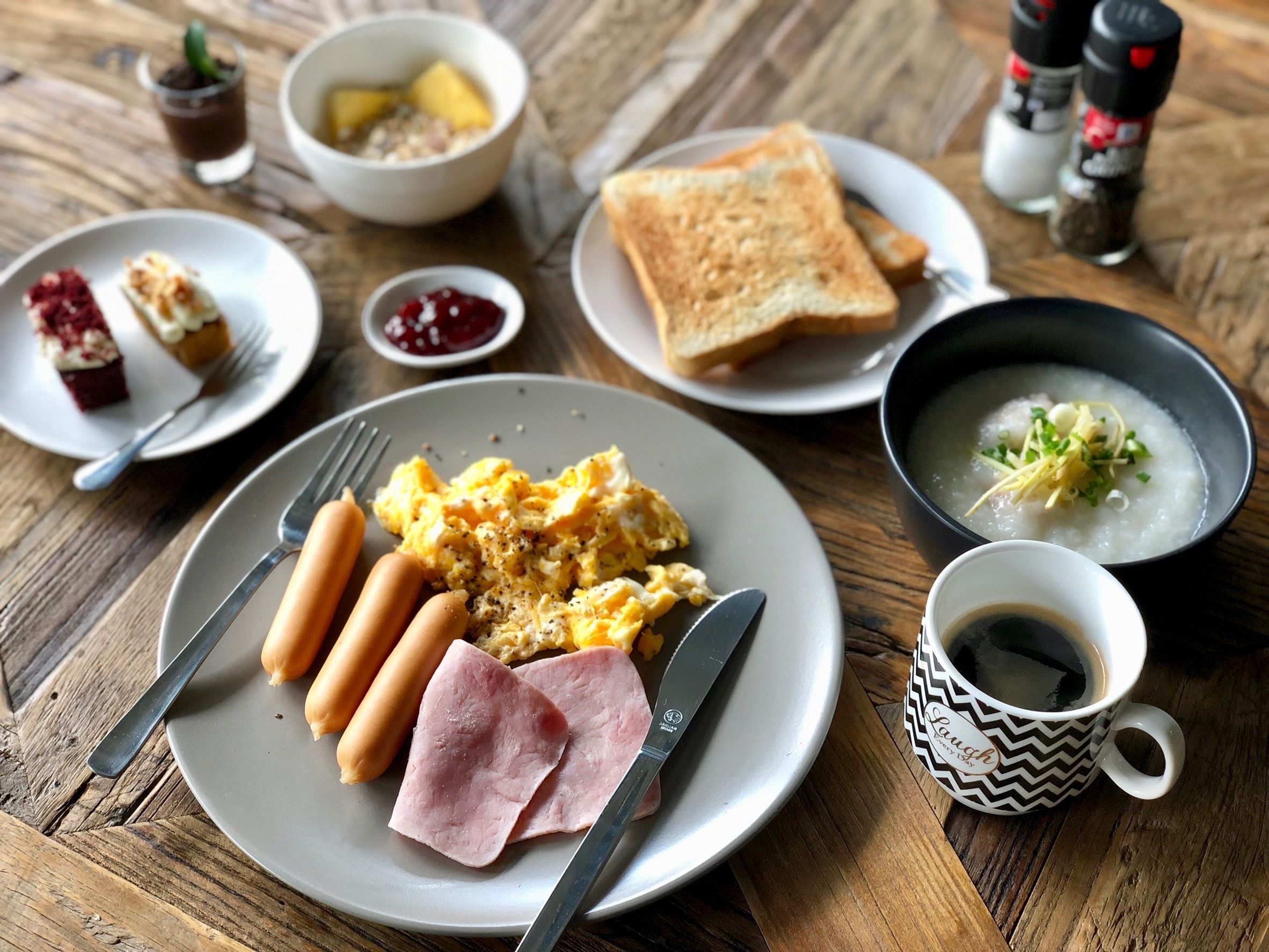 Een ontbijtbord met roerei, worstjes, ham, toast en een kom soep.