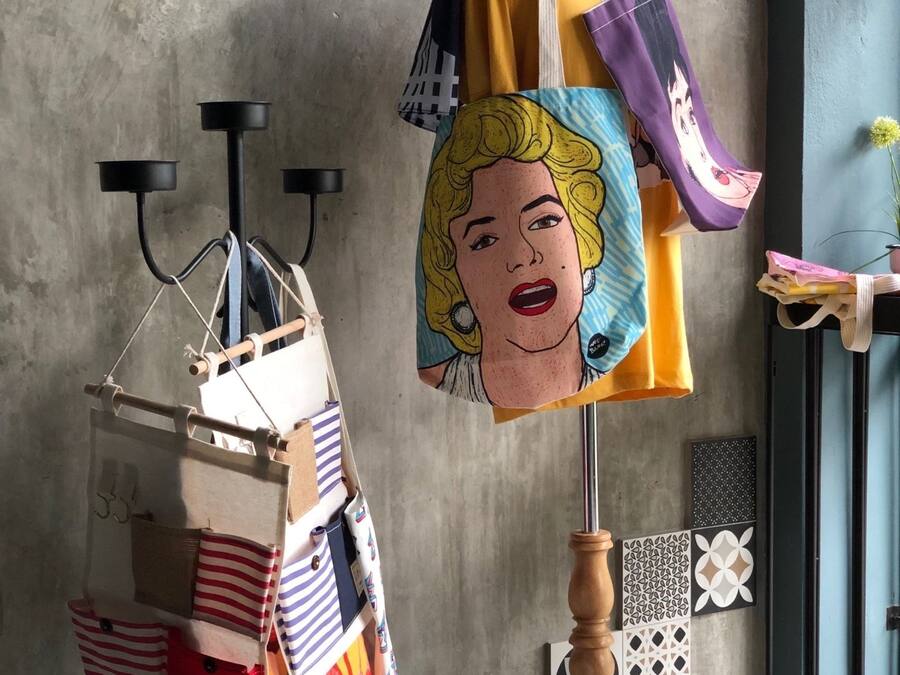 A mannequin with a colorful jacket, a rack of striped bags, and patterned tiles on the floor.