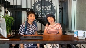 Two individuals seated at a reception desk with a sign reading "Good Light" in the background. - Goodnight Poshtel (Hat Yai)