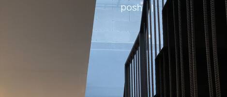 Um interior moderno com uma grande janela exibindo os textos 'Good Night' e 'posh', um corrimão preto e três luminárias de teto.