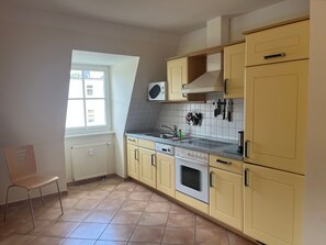Une cuisine avec des meubles de couleur jaune, une cuisinière et une fenêtre.