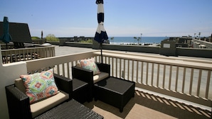 A rooftop terrace with outdoor furniture, a view of the ocean, and a clear sky. - B306 - Luxury Penthouse with spacious deck. Enjoy ocean View from Deck lounge sun bed (Oceanside)